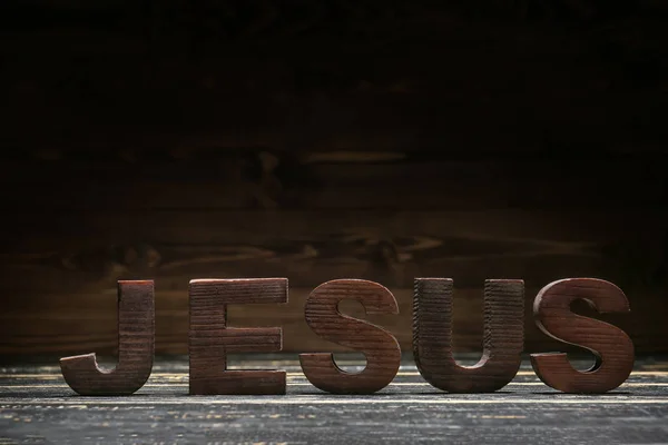 Word JESUS on wooden table against dark background — 스톡 사진
