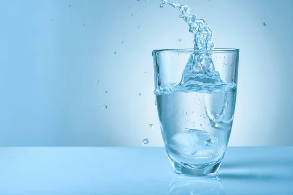 Glass of fresh water with splash on color background — Stock Photo, Image