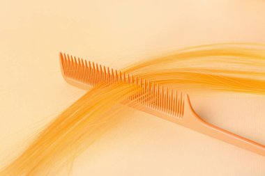 Hair strand and comb on color background