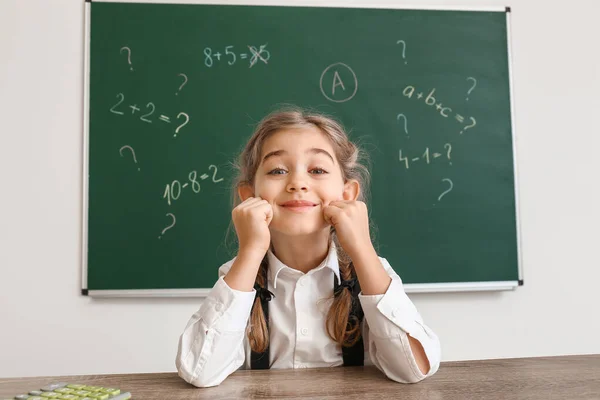 Gadis sekolah kecil duduk di meja di kelas — Stok Foto