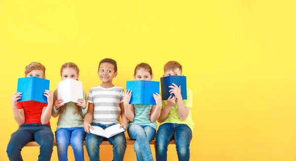 Niedliche kleine Kinder mit Büchern auf farbigem Hintergrund — Stockfoto