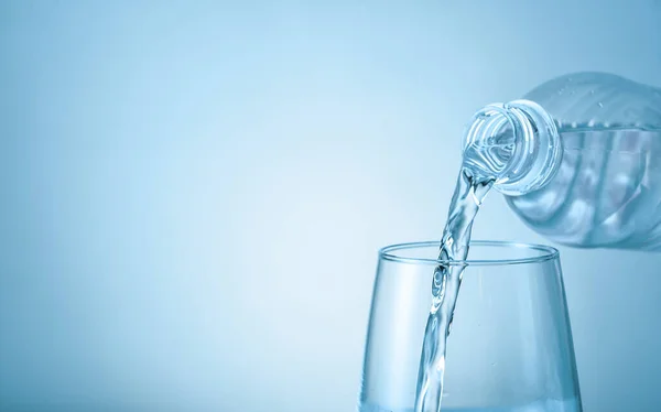 Gieten van zoet water in glas op kleur achtergrond — Stockfoto