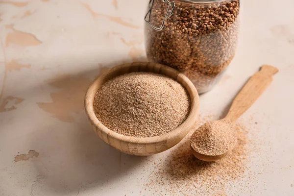 Jar with grains and bowl of buckwheat flour on table — Stock Photo, Image