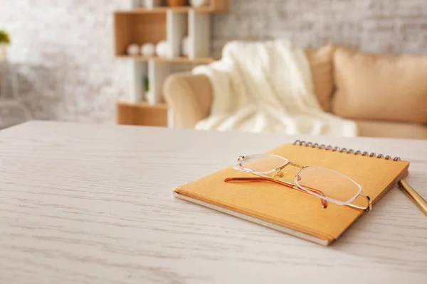 Stylish eyeglasses with notebook on table at home — Stock Photo, Image