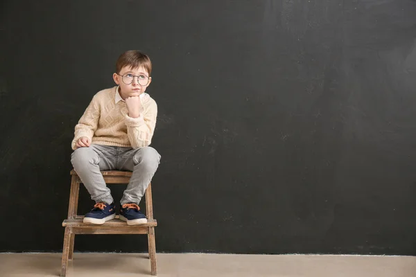 Kisiskolás fiú ül a tábla mellett az osztályteremben — Stock Fotó