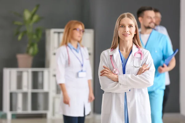 Female doctor with colleagues in hall of clinic — Stock Photo, Image