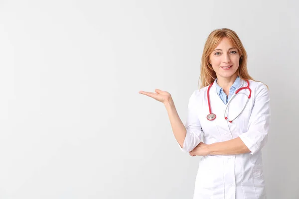 Portret van vrouwelijke arts toont iets op lichte achtergrond — Stockfoto