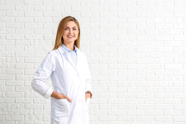 Portré női orvos fehér tégla háttér — Stock Fotó