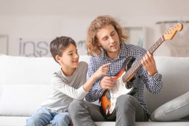 Bir adam ve küçük oğlu evde gitar çalıyorlar.