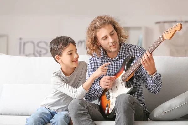 Hombre y su pequeño hijo tocando la guitarra en casa — Foto de Stock