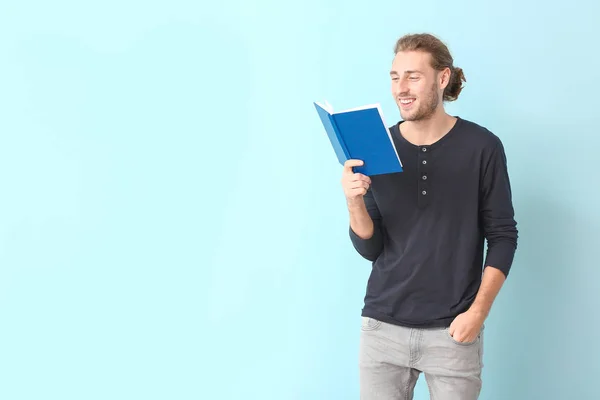 Schöner Mann mit Buch auf hellem Hintergrund — Stockfoto