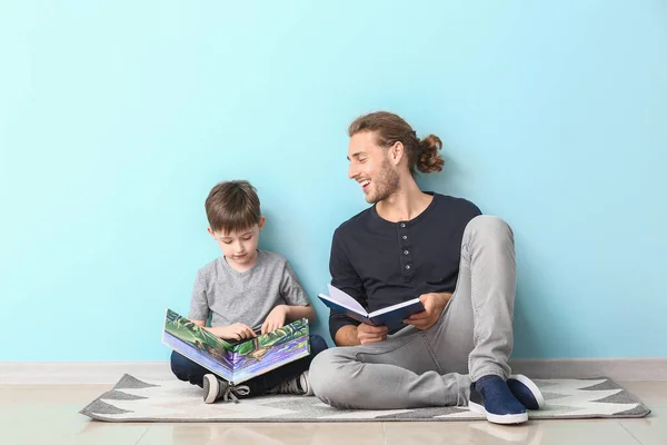 Far och hans son läser böcker nära ljusväggen. — Stockfoto