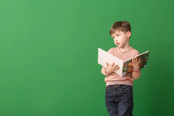 Kleiner Junge mit Buch auf farbigem Hintergrund — Stockfoto