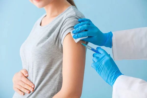 Врач вакцинирует беременную женщину на цветном фоне — стоковое фото