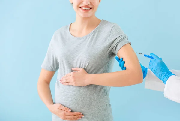 Γιατρός εμβολιασμό έγκυος γυναίκα στο φόντο χρώμα — Φωτογραφία Αρχείου