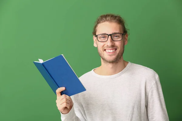 Hezký muž s knihou na barevném pozadí — Stock fotografie