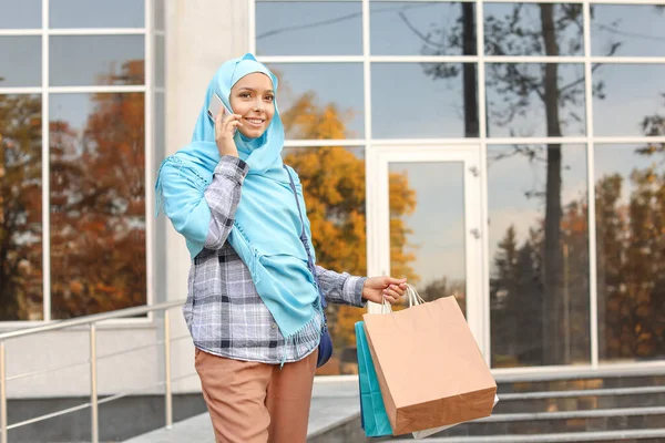 美丽的穆斯林妇女，戴着购物袋，在户外用电话交谈 — 图库照片