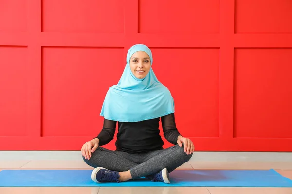 Sportliche muslimische Frau praktiziert Yoga in der Nähe der Farbwand — Stockfoto