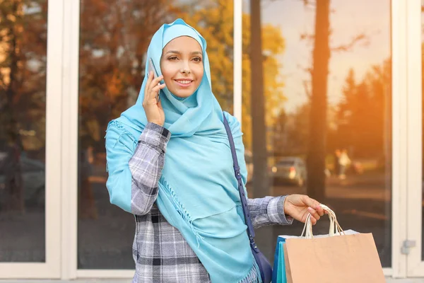 美丽的穆斯林妇女，戴着购物袋，在户外用电话交谈 — 图库照片