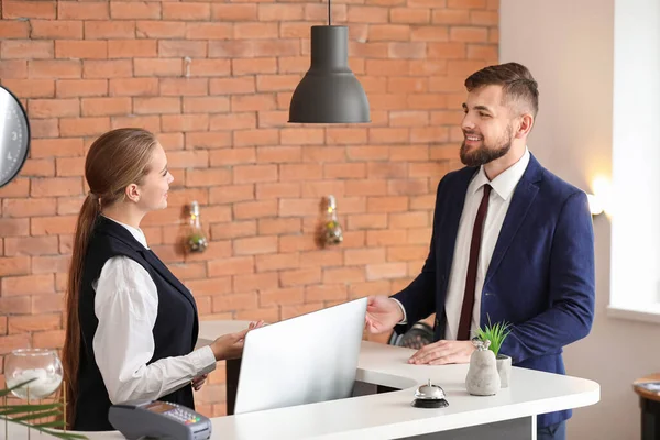 Young female receptionist working with guest in hotel — Stock Photo, Image