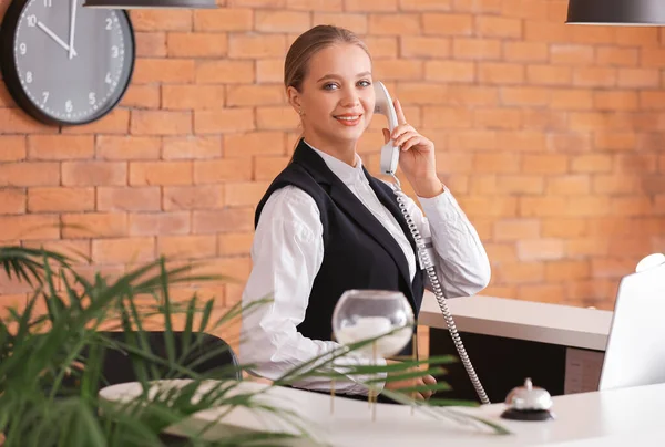 Recepcionista joven hablando por teléfono en el escritorio en el hotel — Foto de Stock