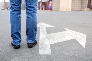 Okları işaretli genç bir adam yolda duruyor. Seçim kavramı