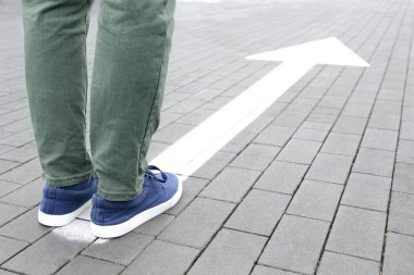 Genç adam ok işaretli bir şekilde yolda duruyor. Seçim kavramı