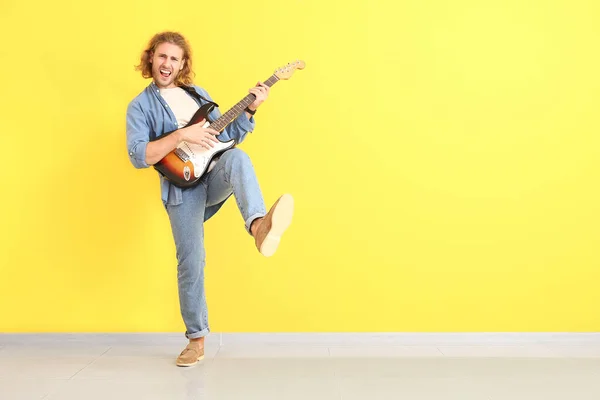 Hombre tocando la guitarra contra la pared de color — Foto de Stock