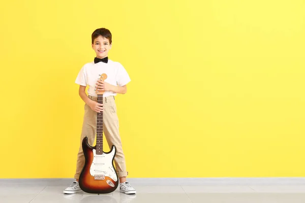 Petit garçon avec guitare près du mur de couleur — Photo