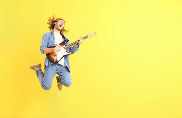 Salto uomo con chitarra su sfondo a colori — Foto Stock