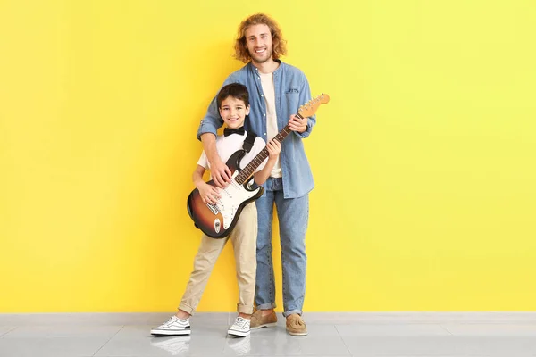 Man and his little son with guitar near color wall — Stock Photo, Image