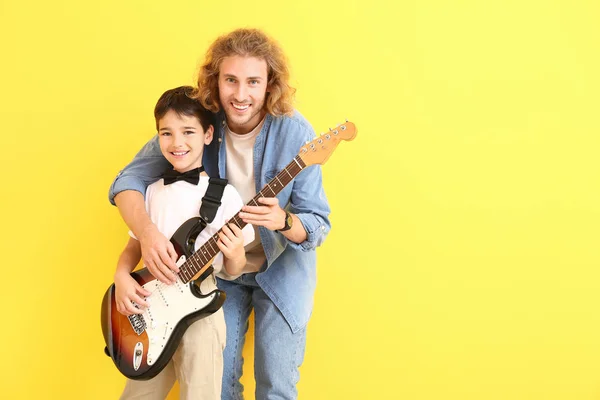 Чоловік і його син з гітарою на кольоровому фоні. — стокове фото