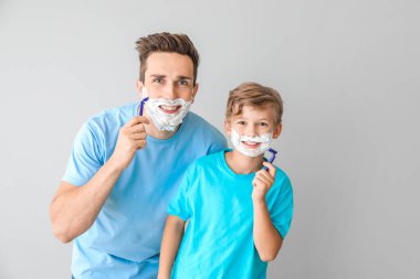 Baba ve küçük oğlu gri arka plan aleyhine tıraş