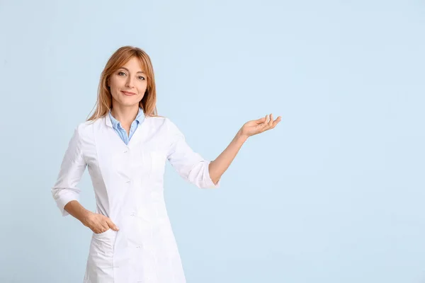 Portrait of female doctor showing something on color background — Stock Photo, Image