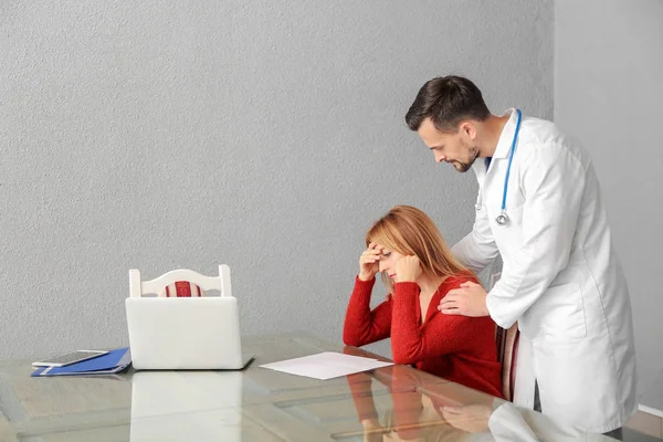 Male doctor calming sad patient in clinic — Stock Photo, Image