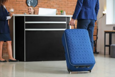 Genç adam resepsiyona gidip otelde bir oda ayırtacak.