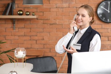 Otelin Resepsiyon, telefonla konuşurken genç kadın resepsiyonist