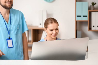 Klinikte masa başında çalışan erkek ve kadın resepsiyonistler