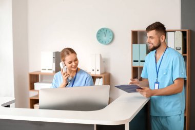 Klinikte resepsiyon masası yakınında erkek doktor