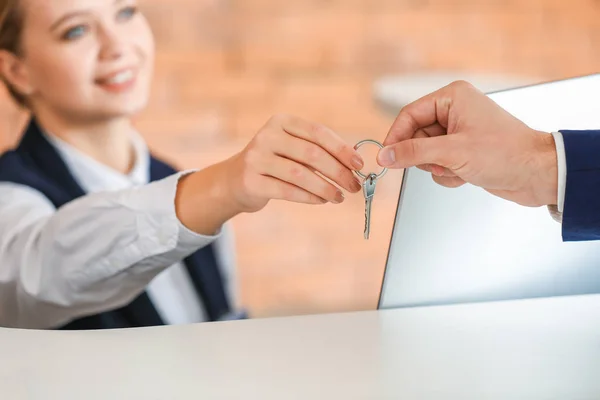 La recepcionista femenina entrega la llave de la habitación al hombre en el hotel — Foto de Stock