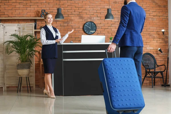 Young man going to reception desk for booking a room in hotel