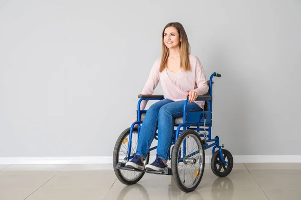 Jovem deficiente em cadeira de rodas perto de parede leve — Fotografia de Stock