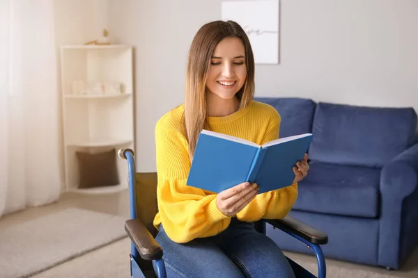 Behinderte junge Frau im Rollstuhl liest zu Hause Buch — Stockfoto