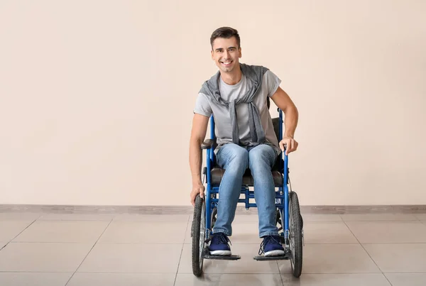 Handicapped young man in wheelchair near color wall — Stock Photo, Image