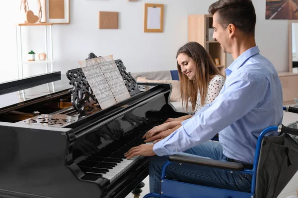 Woman teaching young man in wheelchair to play piano — Stock Photo, Image