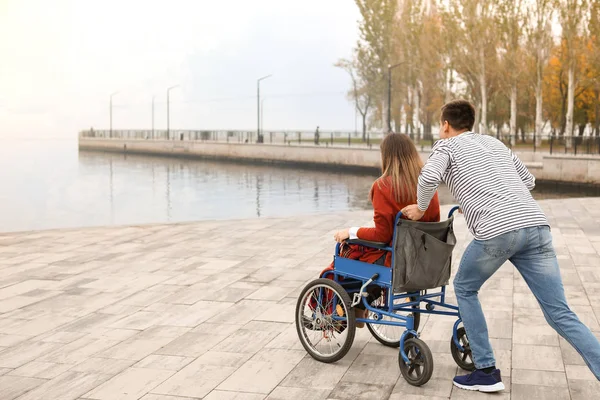 Αναπηρίας νεαρή γυναίκα σε αναπηρική καρέκλα και ο σύζυγός της κοντά στο ποτάμι — Φωτογραφία Αρχείου