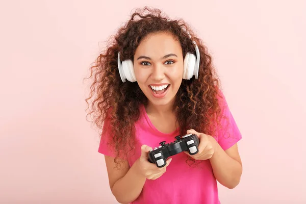 Young African-American woman playing video game on color background — Stock Photo, Image