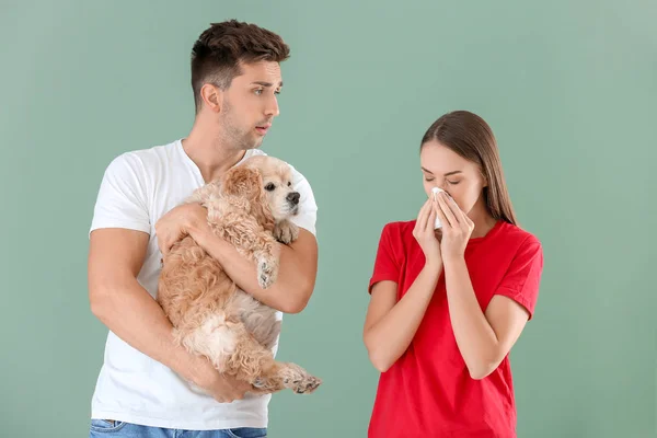 Jovem com cão e sua esposa sofrendo de alergia ao animal de estimação no fundo de cor — Fotografia de Stock