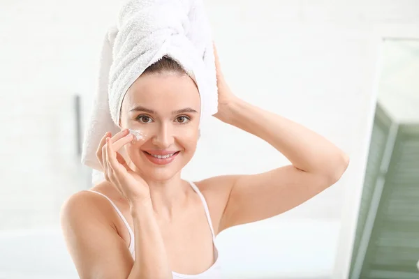 Hermosa joven aplicación de crema en casa — Foto de Stock