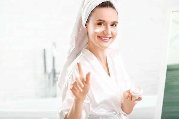 Beautiful young woman applying cream at home — Stock Photo, Image